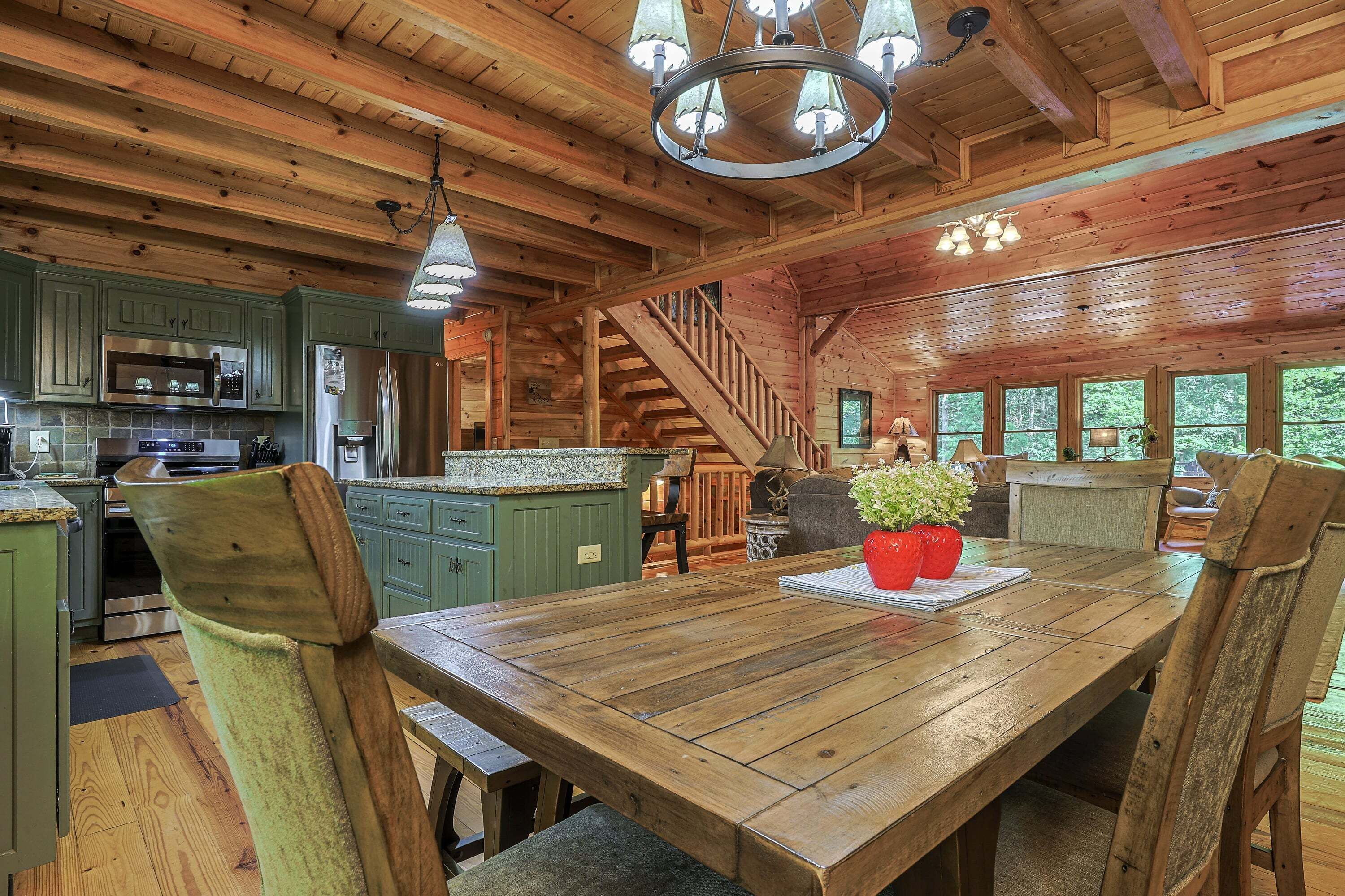 A wooden cabin interior with a kitchen, dining area, and a staircase.