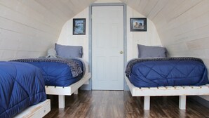 A bedroom with two beds, a wooden floor, and a door. - For less than two hotel rooms, stay on the Spit and sleep 7!  (Homer)