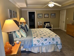 A bedroom with a bed, two lamps, a chair, a dresser, and a ceiling fan.