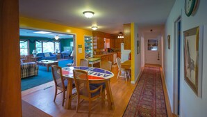 A cozy living room with a blue sofa, a dining table with chairs, and a kitchen area with wooden cabinets and a refrigerator.