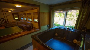 A room with a large bathtub, a dining table, and a seating area with a couch and chairs.