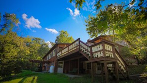 A wooden cabin with a porch and a staircase leading to a deck.