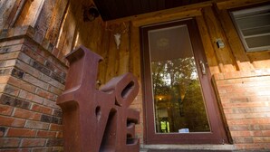 A wooden building entrance with a large glass door and a metal sculpture.