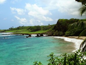 A coastal landscape with clear turquoise waters, a sandy beach, and lush greenery. - Beautiful Home in paradise! (Hana)