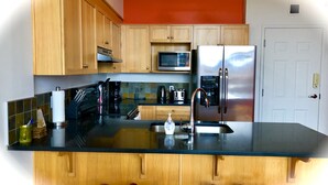 Eine Küche mit Holzausstattung, einem Edelstahlkühlschrank, einer Mikrowelle und einer Kaffeemaschine.