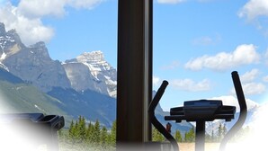 Blick auf eine Berglandschaft durch ein Fenster, im Vordergrund ein Laufband.