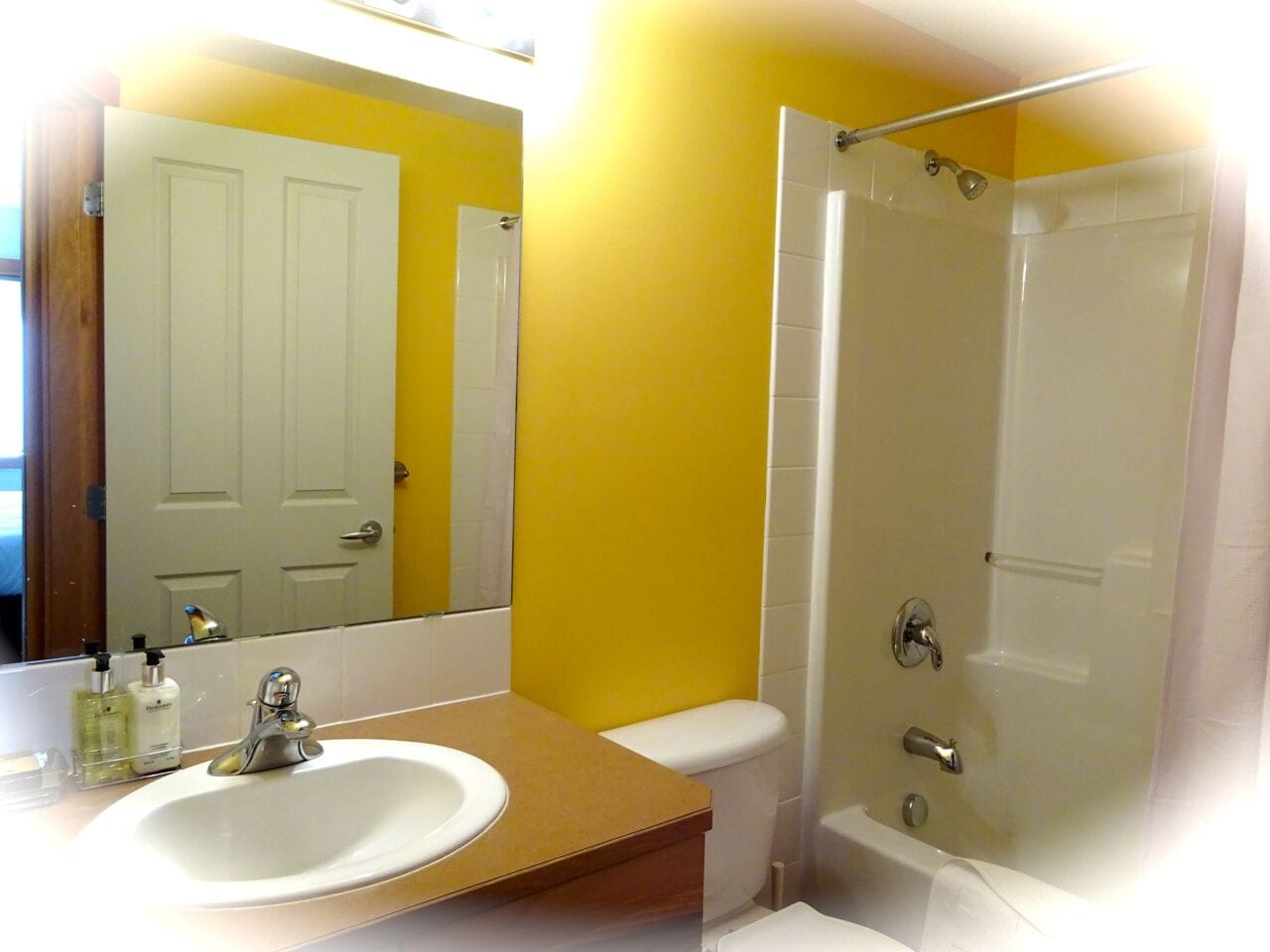 A bathroom with a white sink, mirror, and shower.