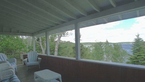 A covered deck with wicker furniture and a view of a lake. - Linekin Vista - 3BDR Waterfront Cottage on Linekin Bay with Private Beach! (East Boothbay)