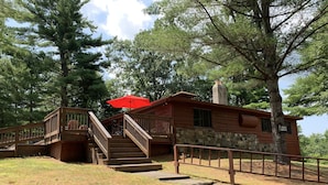 A cabin with a stone foundation, wooden exterior, and a staircase leading to a deck.