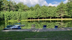 A lakeside setting with boats and chairs by the water, surrounded by dense trees.
