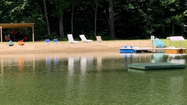 A calm outdoor swimming area with lounge chairs and a small boat dock.