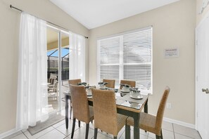 Enjoy meals in this dining area with a glass-top table and wicker chairs, leading to a patio.