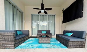 A balcony with wicker furniture, a ceiling fan, and a view of the pool.