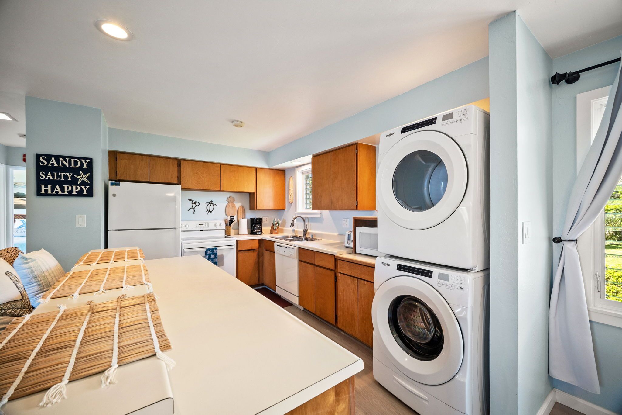 A modern kitchen with wooden cabinets, a built-in washing machine, and a dining area with a table and chairs.