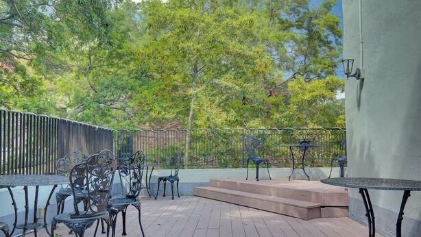 An outdoor patio with metal chairs and tables, a wooden deck, and a metal fence. - The Carolina Suite - Heart of Historic Charleston (Charleston)