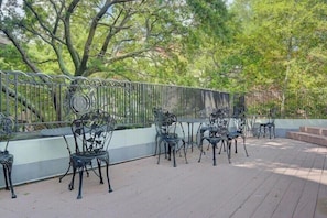 An outdoor patio with metal chairs and tables, surrounded by a metal fence and trees. - The Carolina Suite - Heart of Historic Charleston (Charleston)