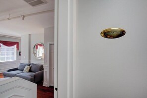 A room with a grey sofa, a white door, and a sign that reads 'CAROLINA SUITE'.