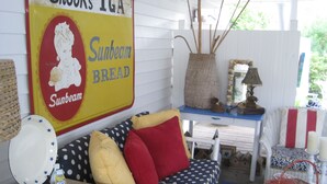 A cozy room with a polka dot sofa, a vintage Sunbeam Bread sign, a wicker basket, and a wicker chair. - Twin Palms Cottage (Tybee Island)
