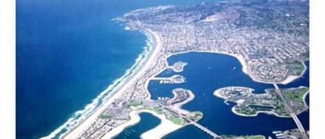 An aerial view of a coastal city with a marina, urban areas, and a beach.