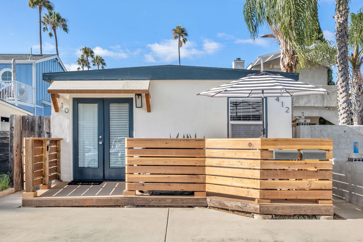 Una casa moderna con una recinzione in legno, una porta e un piccolo patio.