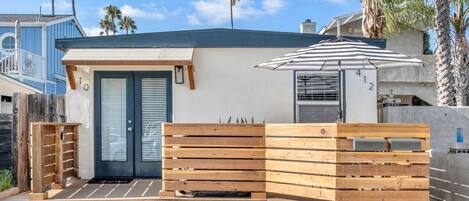 A modern house with a wooden fence, a door, and a small patio area.