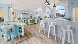 Une cuisine spacieuse dotée d’un îlot central, de tabourets de bar et de luminaires suspendus.