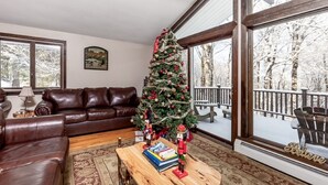 A cozy living room with a Christmas tree, leather sofa, and a wooden coffee table.