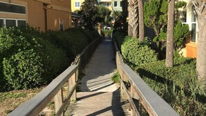 A wooden boardwalk leading to a building with a yellow facade and arched windows. - Spectacular Ocean View! Great Location On 30A   King Bed ,Newly Remodeled! (Santa Rosa Beach)