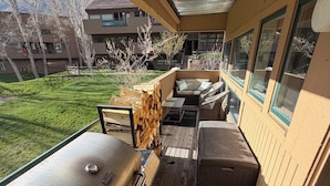 A covered deck with a grill, seating area, and a view of the surrounding landscape.