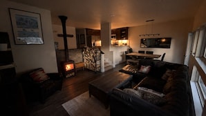 A cozy living room with a fireplace, a sofa, and a dining area.