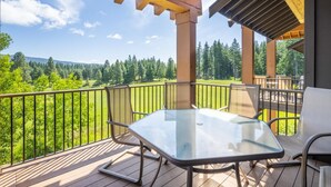 A covered outdoor area with a glass table and chairs, overlooking a forested landscape. - Family Friendly w/ Suncadia Pool Access (Cle Elum)