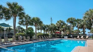 A swimming pool with clear blue water, surrounded by palm trees and lounge chairs. - Caribbean Dunes 2BR/2BA with The Best Gulf View (Destin)