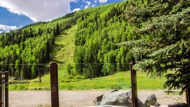 A hot tub with a control panel, surrounded by a natural landscape with a mountain and trees in the background. - ABSOLUTE SKI-IN/OUT IN TOWN! GREAT VIEWS! HOT TUB! PRIVATE GARAGE! 2 BED + LOFT! (Telluride)