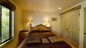 A bedroom with a large bed, two bedside lamps, a nightstand, a window with blinds, and a door. - ABSOLUTE SKI-IN/OUT IN TOWN! GREAT VIEWS! HOT TUB! PRIVATE GARAGE! 2 BED + LOFT! (Telluride)