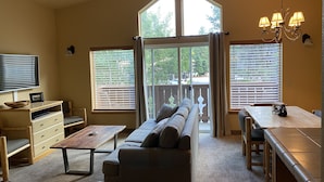 A spacious living area with a sofa, coffee table, TV, and dining table. - Icicle Village Resort, Luxury Queen Suite Condo. Just 1/2 mile from down town (Leavenworth)