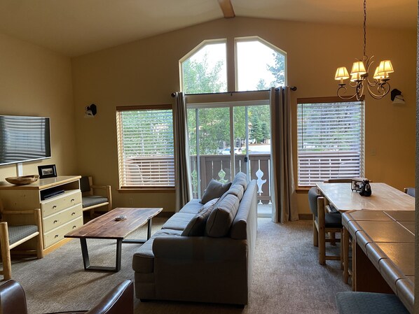 A spacious living area with a sofa, coffee table, TV, and dining table.