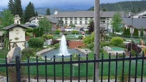 A courtyard with a fountain, surrounded by greenery and a building with a white facade. - Icicle Village Resort, Luxury Queen Suite Condo. Just 1/2 mile from down town (Leavenworth)