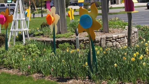 Une enseigne indiquant « Top of the Hill Shops », avec un mât pour drapeau et des sculptures d’oiseaux décoratives.