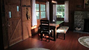 A rustic wooden room with a dining table, chairs, a bench, and a fireplace.