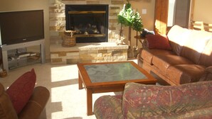 A living room with a stone fireplace, leather sofa, and a flat-screen TV. - 2 Masters, Private Hot Tub, Superb Views - Close to WP Resort Skiing, Biking (Winter Park)