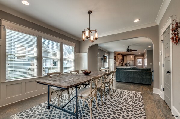 A dining area with a wooden table, chairs, and a patterned rug.