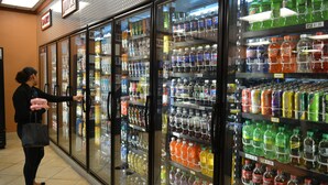 Een gekoeld drankendisplay in een winkel met verschillende frisdranken en vruchtensappen.