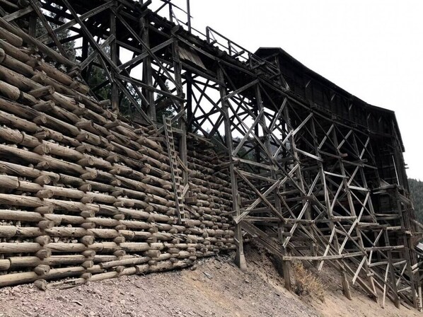 A wooden structure with a lattice framework and a wall of logs. - Gorgeous riverfront, 4-BR (2-master suite) home! (Southfork)