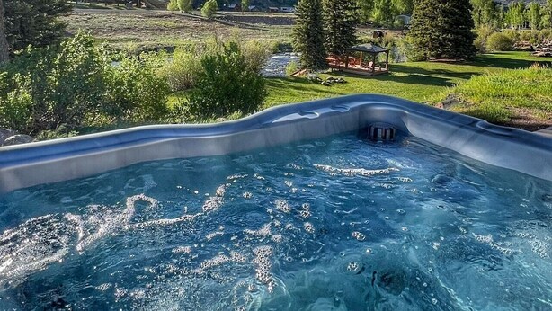 A hot tub with a view of a mountainous landscape and a river. - Gorgeous riverfront, 4-BR (2-master suite) home! (Southfork)