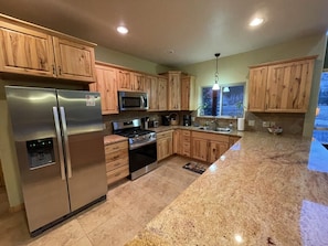 Enjoy cooking in this well-equipped kitchen with a central island, stainless steel appliances, and a granite countertop.