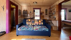 Una stanza accogliente con un divano blu, pareti in legno, una ventola a soffitto e una libreria.