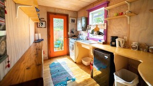 Una cucina compatta con mobili in legno, un fornello, un lavello e un frigorifero.