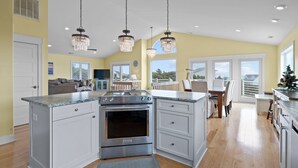 A spacious kitchen with a central island, stainless steel appliances, and pendant lighting. - 3rd Row Oceanview,Private pool,hot tub,pet friendly,very short walk to beach (Emerald Isle)