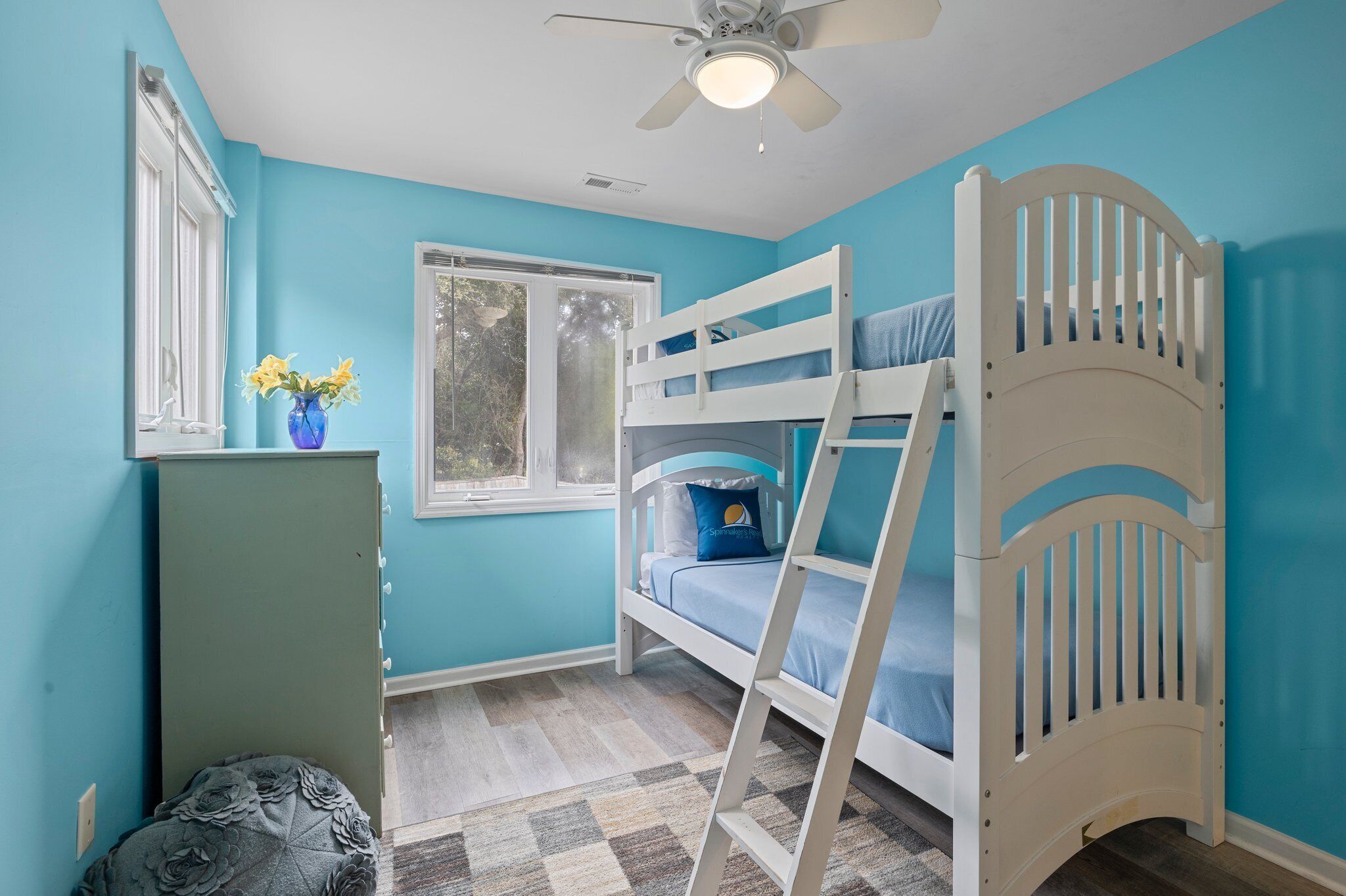 A child’s bedroom with a bunk bed, a window, and a ceiling fan.