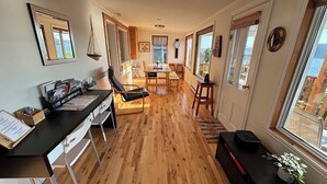 A spacious living area with a wooden floor, a dining table, and a black sofa.